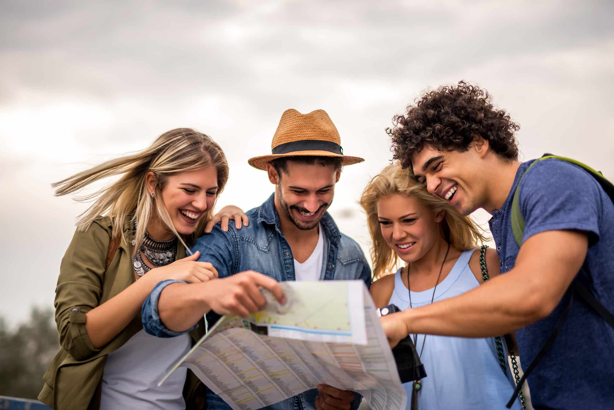 Vier junge Leute die auf einer Karte schauen, fröhliche Gesichter